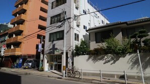 A multi-story building with a white facade and a grey lower section. - 3A Spacious room with Built-in Kitchen (Ōsaka-shi)