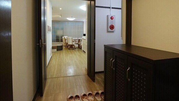 A hallway with a wooden floor leading to a dining area with a table and chairs. A cabinet with drawers is visible on the right. - 3A Spacious room with Built-in Kitchen (Ōsaka-shi)