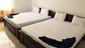Two single beds with wooden frames and white bedding, a blue towel on the left bed, and a window with curtains. - Hotel Sisara (Kataragama)