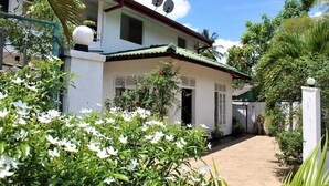 A white building with a green roof, satellite dishes, and a paved entrance. - Hotel Sisara (Kataragama)