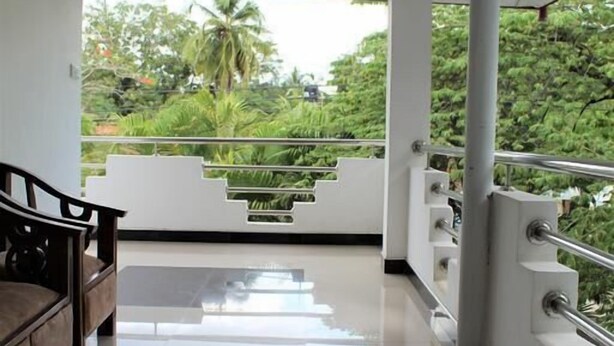A modern interior with a polished floor, a wooden bench, and a view of greenery outside. - Hotel Sisara (Kataragama)