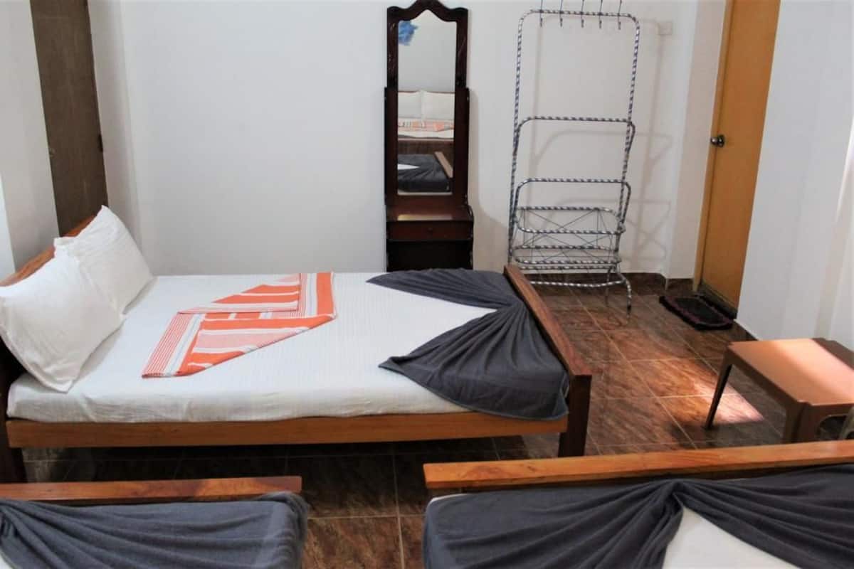 A bedroom with a bed, a wooden nightstand, a mirror, and a metal drying rack.