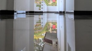 A corridor with reflective flooring, white walls, and a view of greenery outside. - Hotel Sisara (Kataragama)