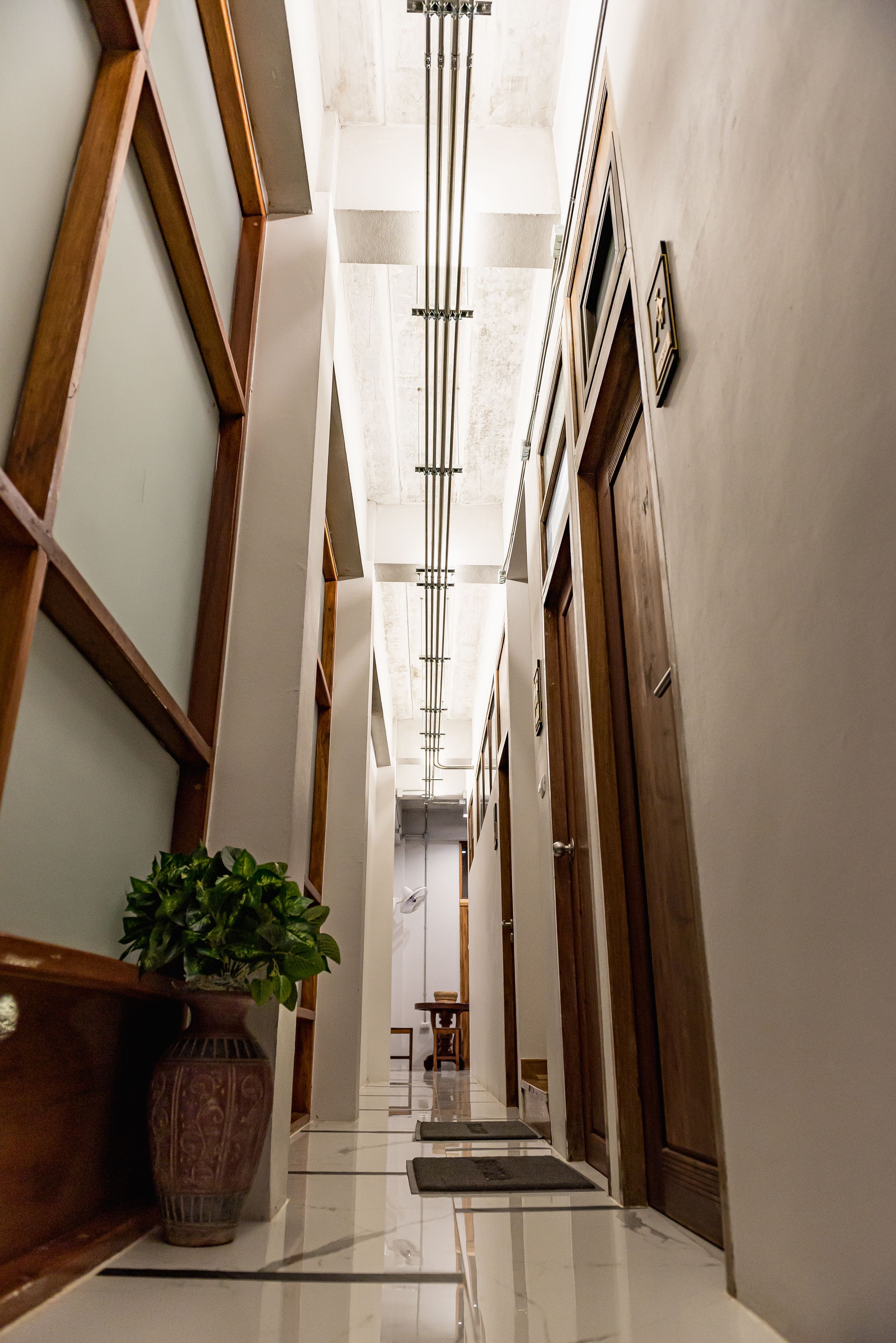 A hallway with a wooden bench, a potted plant, and a door with a handle.
