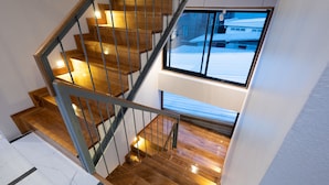A wooden staircase with metal railings and a view of a snowy landscape through a window. - U Chiangkhan Hotel (Chiang Khan)
