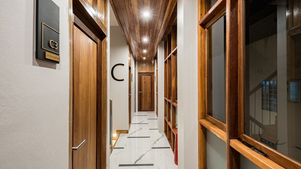 A hallway with wooden doors, a marble floor, and a fire extinguisher. - U Chiangkhan Hotel (Chiang Khan)