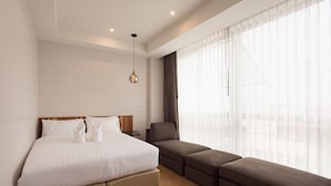 A modern hotel room with a large bed, a sofa, and a window with sheer curtains. - U Chiangkhan Hotel (Chiang Khan)