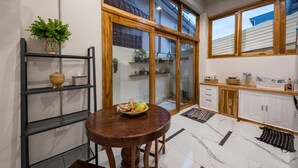 A modern kitchen with a wooden table, a bowl of fruit, and a potted plant. - U Chiangkhan Hotel (Chiang Khan)