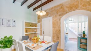 A dining area with a table set for two, a potted plant, and a fruit bowl. - House Ca na Serrieta in the village of Alcudia (Alcúdia)