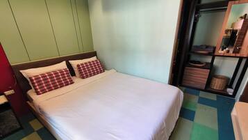 A room with a bed, a wardrobe, and a mirror.