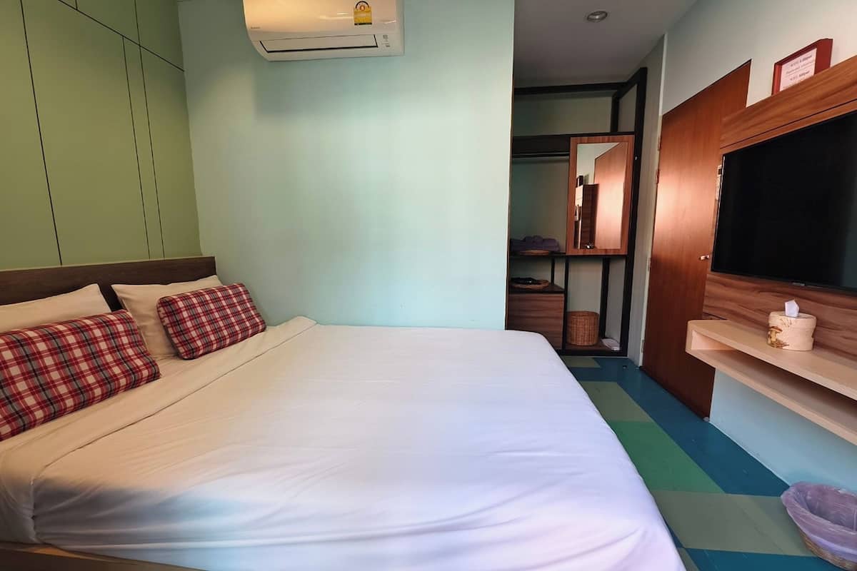 Una habitación de hotel con una cama grande, un televisor y un armario.