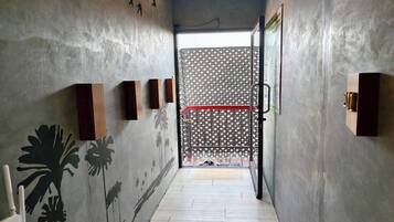 Un couloir étroit, doté d’un sol et de murs en béton, mène à une pièce dont la porte est ornée de motifs.