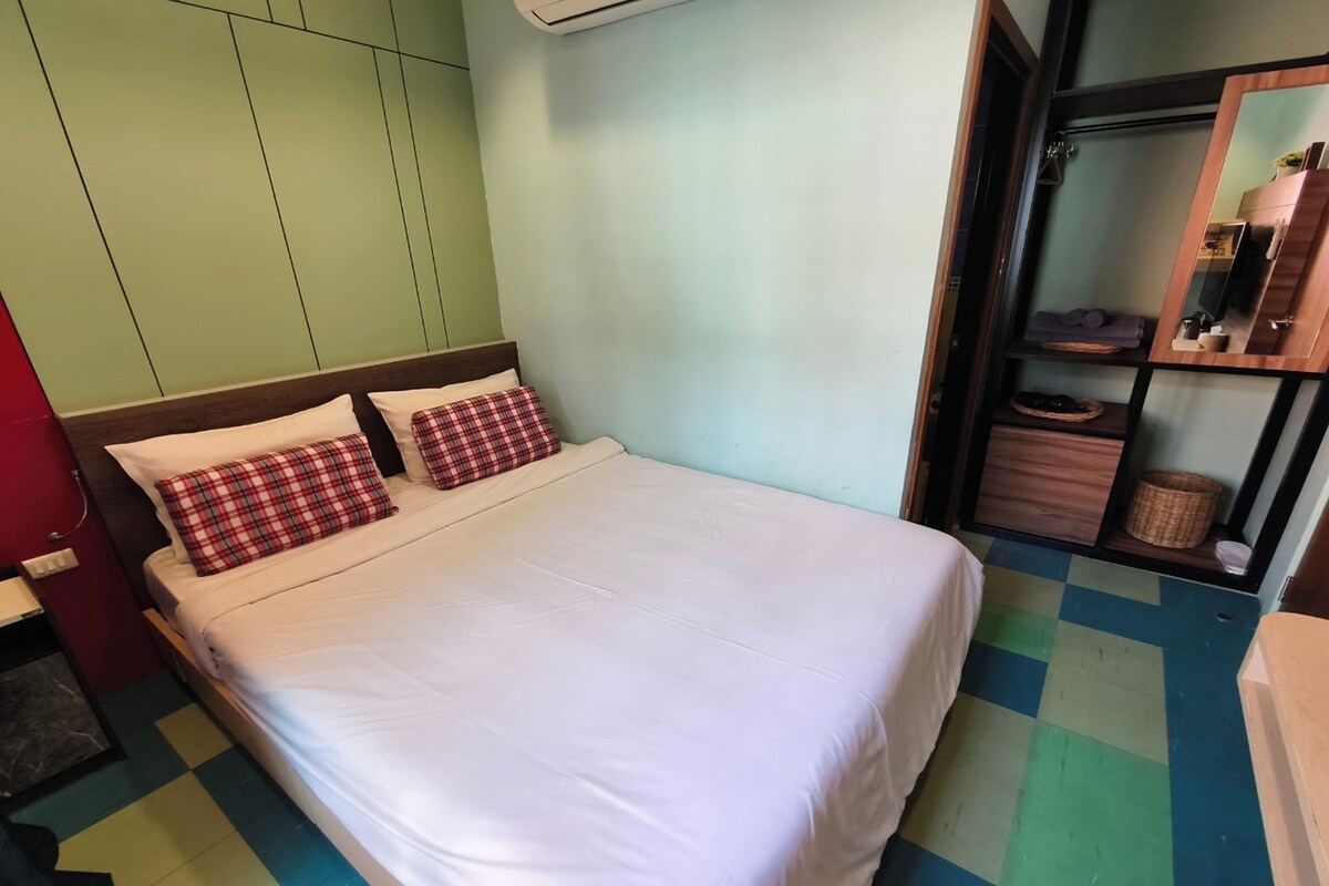 A room with a bed, a wardrobe, and a mirror.