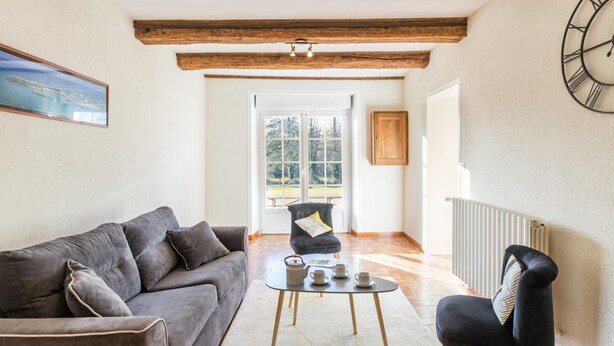 Una sala de estar con un sofá, un sillón, una mesa de centro y un reloj en la pared.