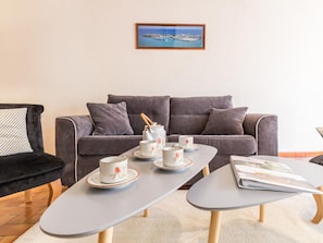 A modern living room with a grey sofa, a coffee table with a magazine, and a framed picture on the wall.
