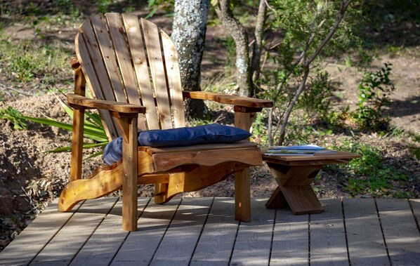 Una silla Adirondack de madera con un cojín azul sobre una terraza de madera.