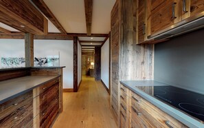A modern kitchen with wooden cabinetry and a large induction cooktop.