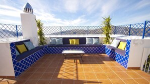 A sunlit terrace with a blue-tiled floor, a central table, and a seating area with cushions. - New luxury villa, 5 bedrooms, 5 bathrooms, private pool (Canillas de Albaida)