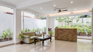 A modern lobby with a sofa, coffee table, and potted plants. - The Residency (Kolkata)