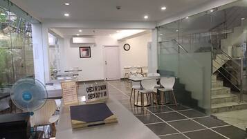A modern indoor space with a check-in/out sign, a clock, and a staircase.