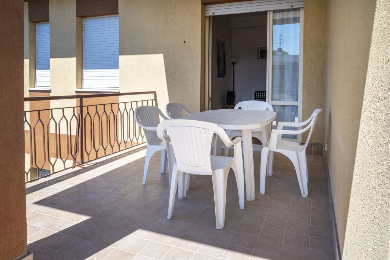 Un balcone con tavolo e sedie, una ringhiera e vista sull'interno dell'edificio.