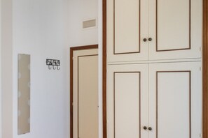 A room with a door, a vent, and a partially visible wall with a sign.