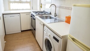 Una cocina compacta con lavavajillas, cocina, fregadero y lavadora.