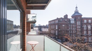 Un balcón con mesa y sillas, con vista a un paisaje urbano con edificios históricos.