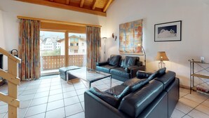 Ein geräumiges Wohnzimmer mit Balkon, Ledersofas, einem Couchtisch und einem Gemälde an der Wand.