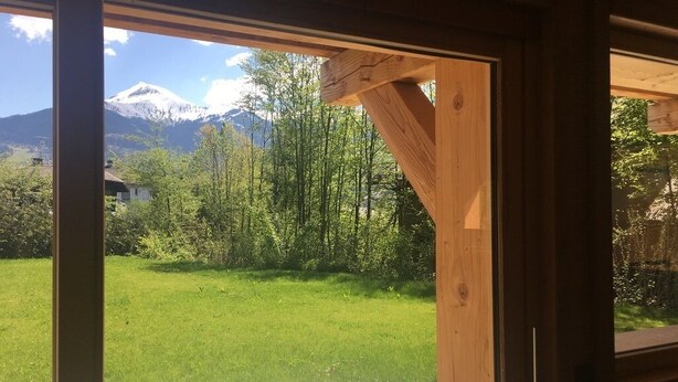 Une terrasse en bois offrant une vue sur une pelouse verdoyante et une montagne en arrière-plan.