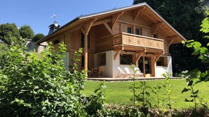 Un chalet en bois doté d’un balcon, d’un coin repas et offrant une vue sur la verdure environnante.