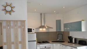 Una cocina moderna con armarios blancos, estufa, horno, microondas y cafetera.