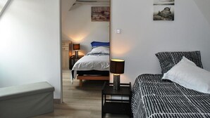 Un dormitorio con cama, mesitas de noche y cuadros en las paredes.