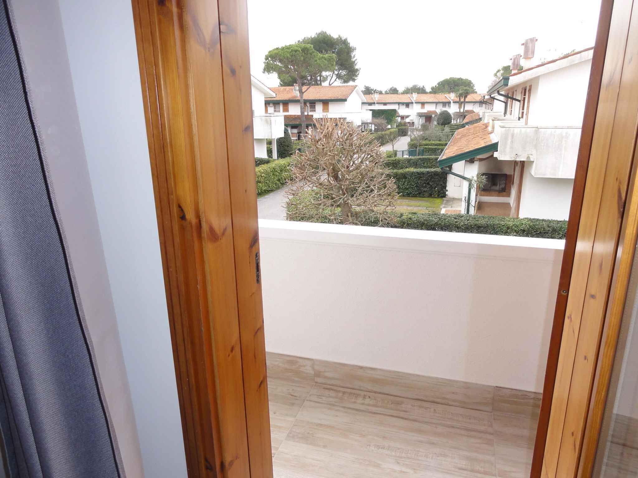 A balcony with a view of a residential area, including houses and a tree.