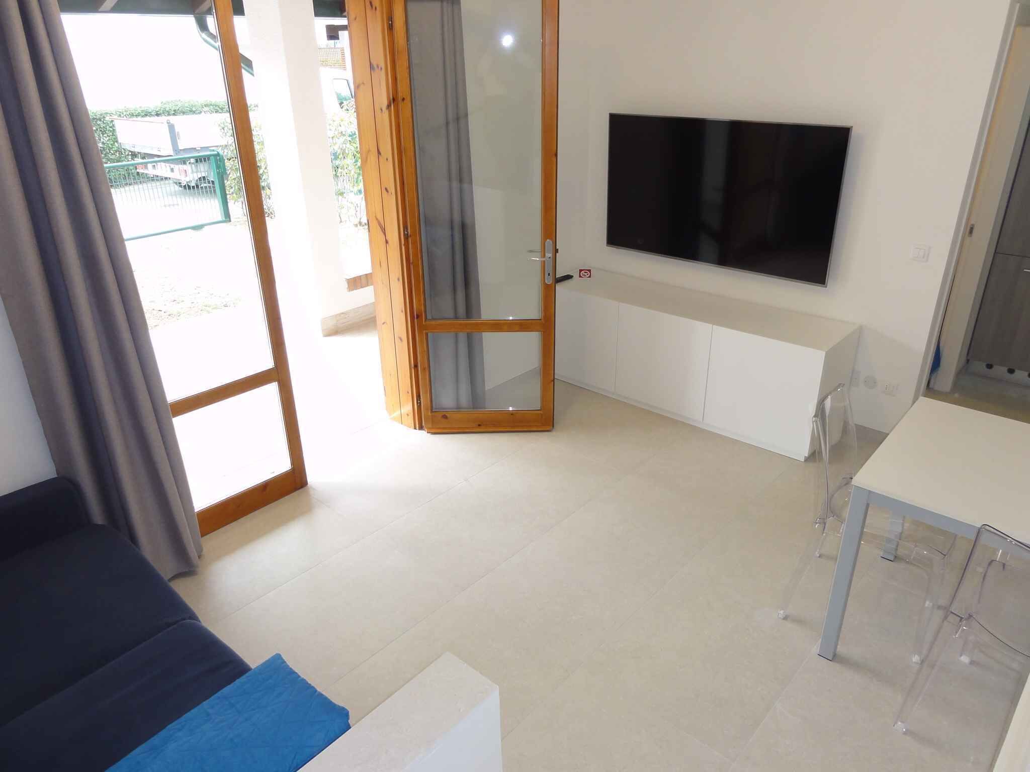 A modern room with a sliding glass door leading to an outdoor area, a flat-screen TV mounted on the wall, and a small table with chairs.