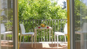 A balcony with two white chairs and a small table with fruit and a glass. - Modern Apartment with Terrace, Swimming Pool&Tennis (Sorrento)