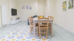 Ein Essbereich mit Tisch und Stühlen, einer Couch und einem Fernseher an der Wand.