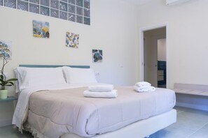 A modern bedroom with a large bed, a potted plant, and artwork on the walls.
