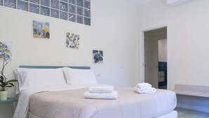 Ein modernes Schlafzimmer mit einem großen Bett, einer Topfpflanze und Kunstwerken an den Wänden.
