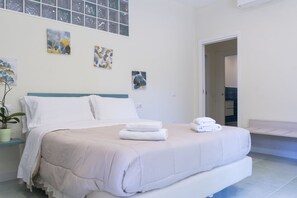A modern bedroom with a large bed, a potted plant, and artwork on the walls.