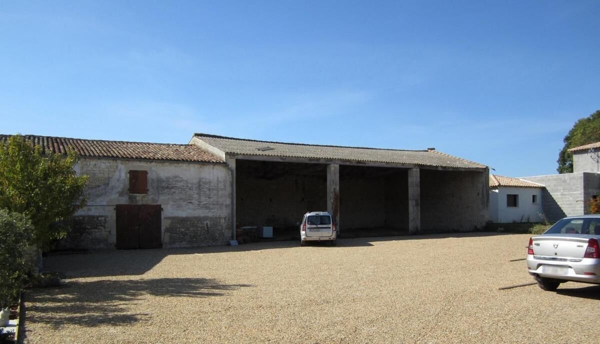 A building with a covered entrance and a gravel driveway.