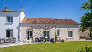 A two-story house with a tiled roof, a covered patio with outdoor furniture, and a well-maintained lawn. - Les Cagouilles (Virson)