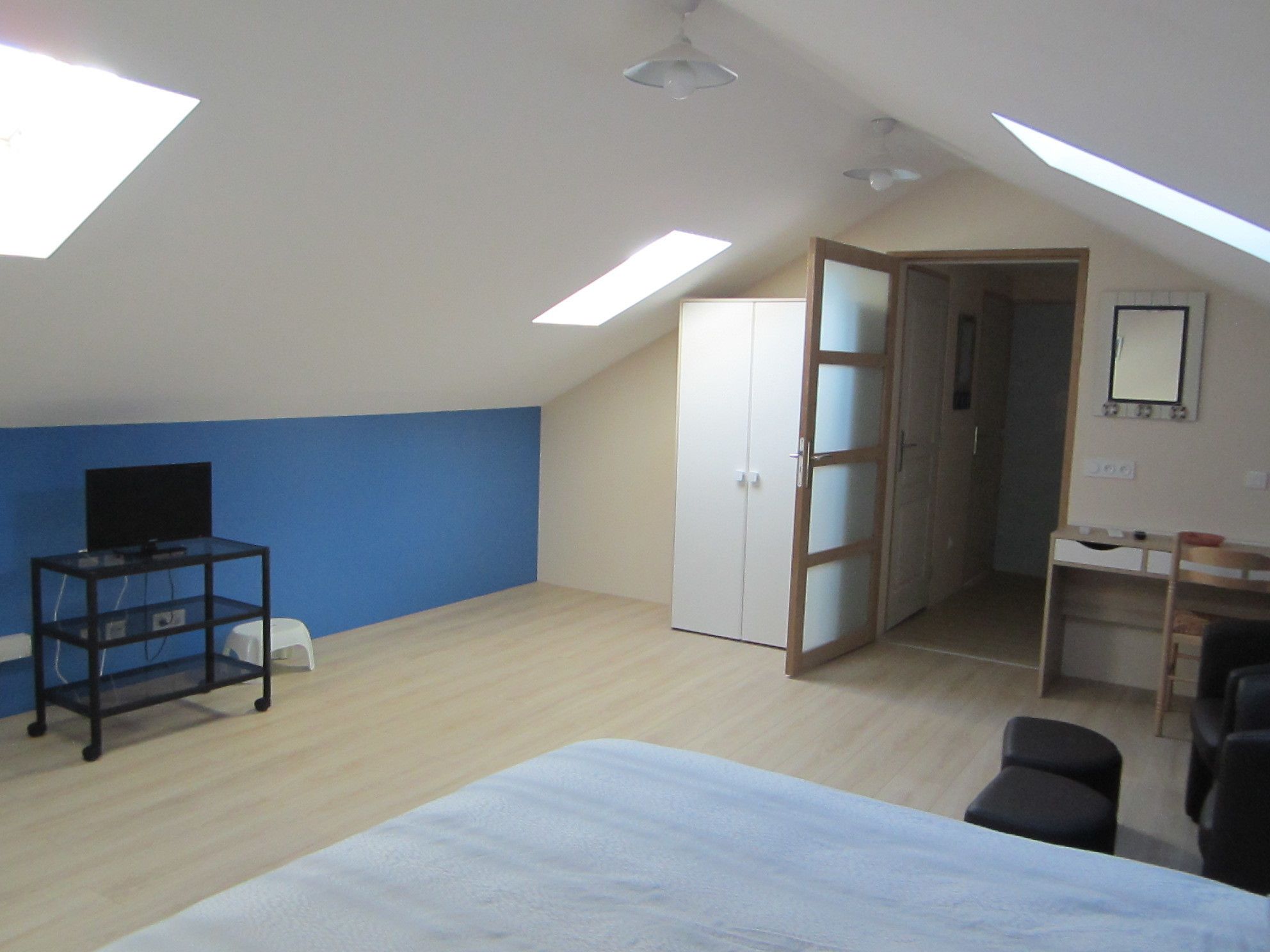Une chambre à coucher avec un lit, un bureau, une armoire et un téléviseur.