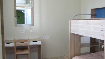A bunk bed room with a desk and chair, a mirror, and a hanging light fixture.