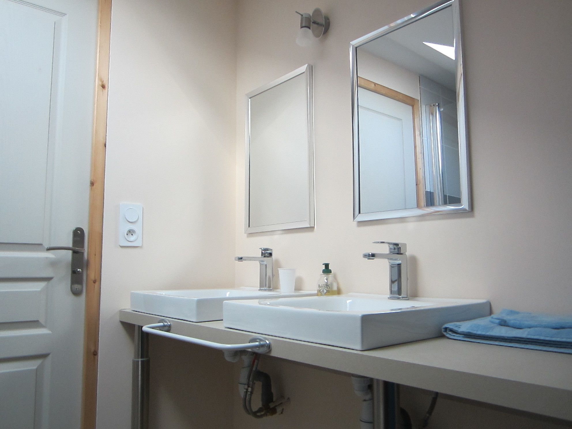 Une salle de bain avec deux lavabos, un miroir et un porte-serviettes.