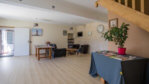 A spacious living room with a wooden floor, a dining table, and a bookshelf. - Les Cagouilles (Virson)