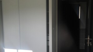 A hallway with a sliding door leading to a room, a dark door at the end, and a tiled floor. - RENTED VILLA F3 RENTED IN THE GREEN AREA (Sainte-Maxime)