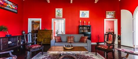 A red-walled living room with a grey sofa, wooden coffee table, and a patterned rug.