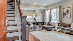 Ein modernes Wohnzimmer mit Treppe, Essbereich und Küche.