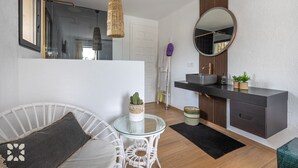 Een moderne badkamer met een douchecabine van glas, een ronde spiegel en een donkere wastafel met een wasbak.